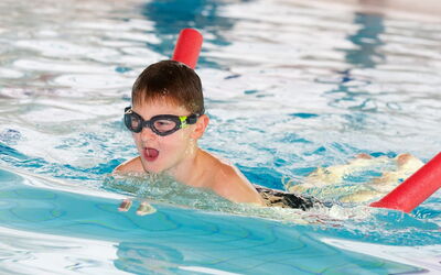 Ein Junge mit Schwimmbrille genießt das Schwimmen im Pool.