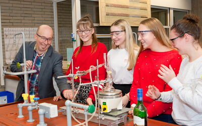 Ein Lehrer zeigt einer Gruppe von Schülerinnen ein Experiment im Chemielabor.