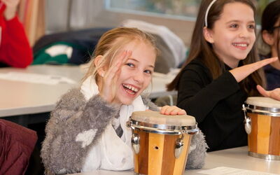 Schülerinnen spielen mit Trommeln in der Schule und bringen Rhythmus und Freude in den Unterricht.