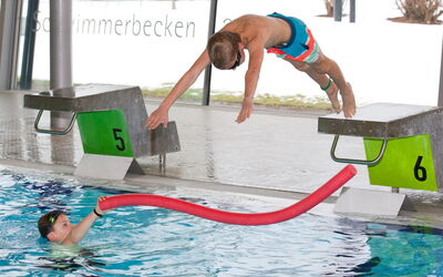 Ein Junge springt fröhlich in den Pool.