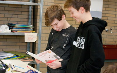 Zwei Jungen schauen auf ein Buch, das sie zusammen lesen, und zeigen großes Interesse an den Bildern.