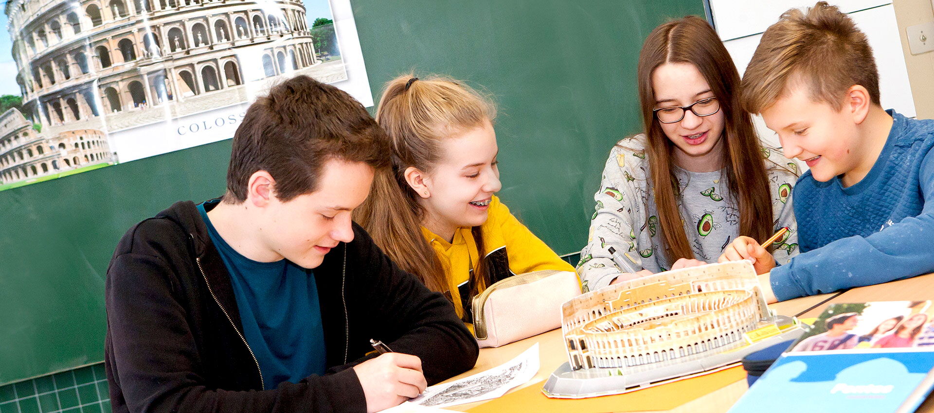 Eine Gruppe von Schülern sitzt an einem Tisch, umgeben von Büchern, und diskutiert im Rahmen des Sprachunterrichts.