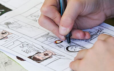 SchülerIn zeichnet mit einem Stift auf Papier und konzentriert sich auf die kreative Arbeit.