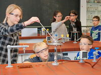 SchülerInnen in einem Chemieraum, die neugierig an einem Experiment arbeiten.