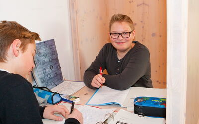 Zwei Schüler machen gemeinsam ihre Hausaufgaben.