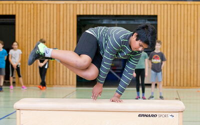 Ein Junge macht einen Sprung über eine Kiste.