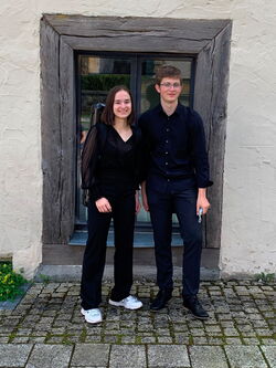 Zwei MusikmentorInnen stehen vor einem Gebäude.