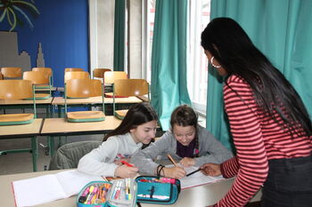 Eine Lehrerin hilft zwei Schülerinnen bei ihren Hausaufgaben in einem Intensivkurs