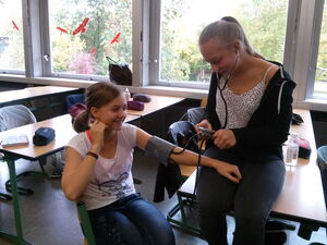 Der Blutdruck einer Schülerin wird in einem Klassenzimmer gemessen