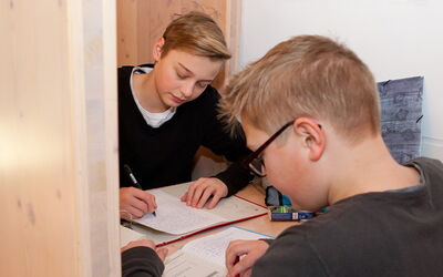 Zwei Jungen machen gemeinsam ihre Hausaufgaben und konzentrieren sich auf ihre Notizen.