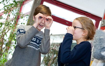 Zwei SchülerInnen schauen durch ein, mit ihren Händen geformtes Fernglas und schauen begeistert.