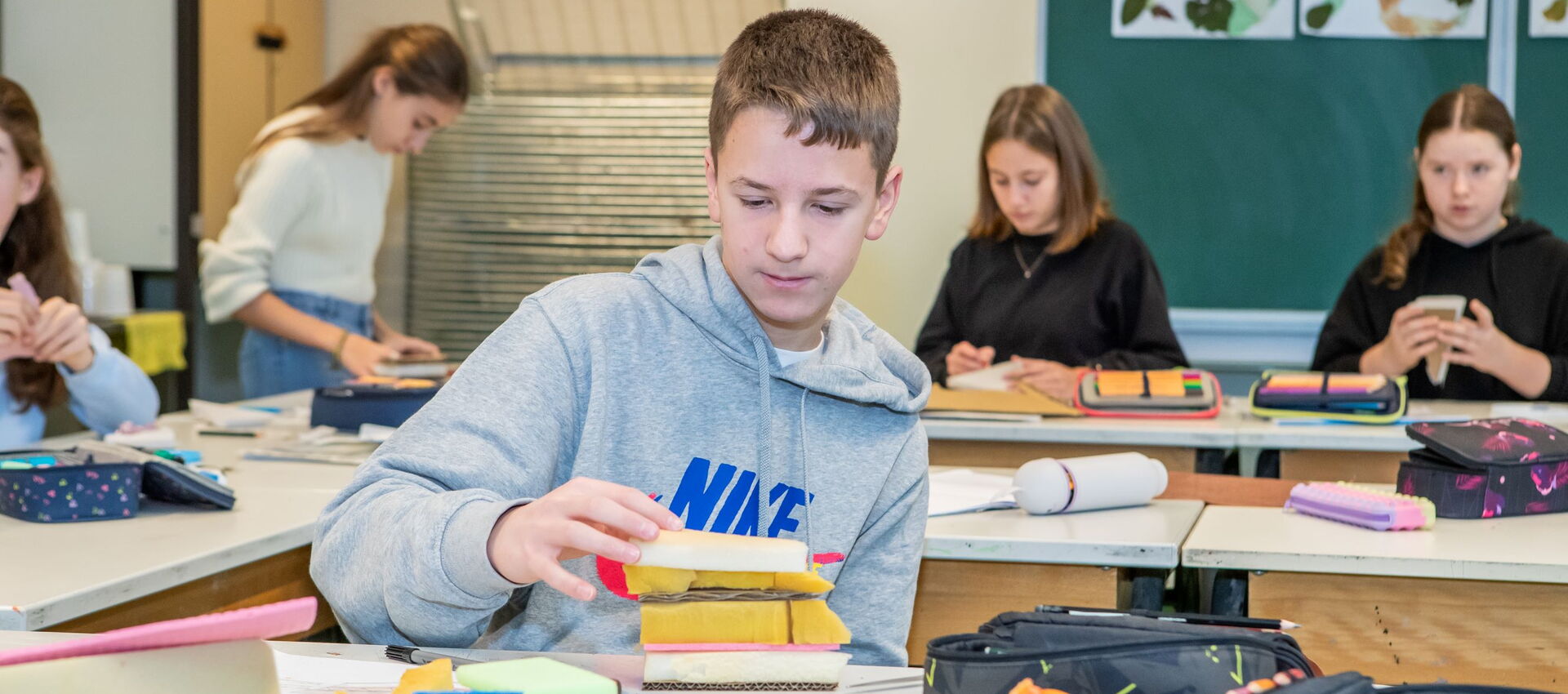 Ein Junge arbeitet konzentriert an seinen Schulaufgaben im Kunstunterricht in einem Klassenzimmer.