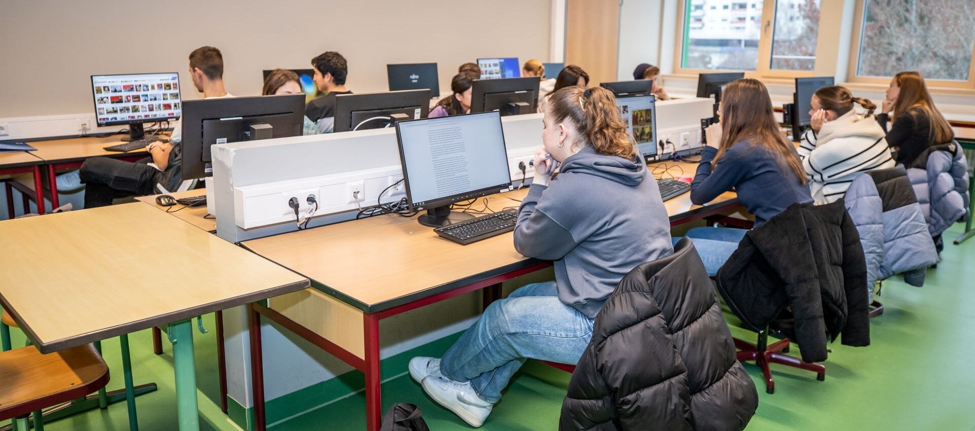 Schüler arbeiten an Computern an ihren Schreibtischen und nutzen moderne digitale Ausstattung im Klassenzimmer.