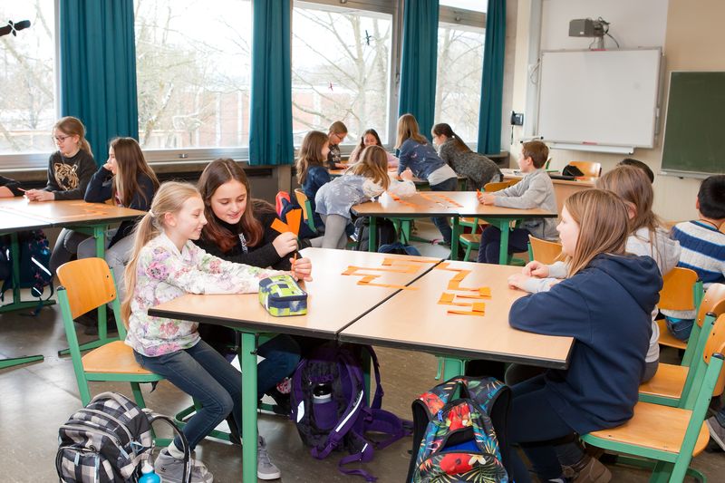 SchülerInnen arbeiten in Gruppen im Klassenzimmer zusammen.