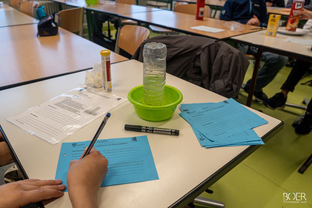 SchülerIn füllt einen blauen Zettel aus bezüglich eines Experimentes